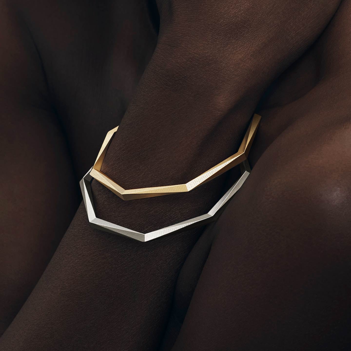 Zwei massive Armreifen mit je 64 geometrischen Facetten, gefertigt aus recyceltem 935 Silber und 750 Gold — nachhaltiger Schmuck von Fine Principles, kombiniert und elegant am Arm getragen.