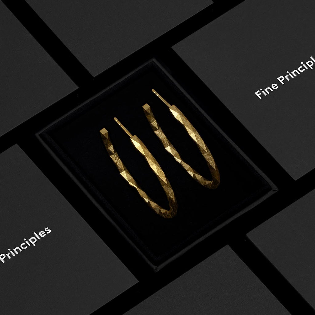 Geometrische Kreolen in Größe L mit 256 Facetten, nachhaltig gefertigt aus recycelten 935 Silber oder 750 Gold — minimalistischer Schmuck von Fine Principles aus Berlin, fotografiert im hochwertigen schwarzen Etui.
