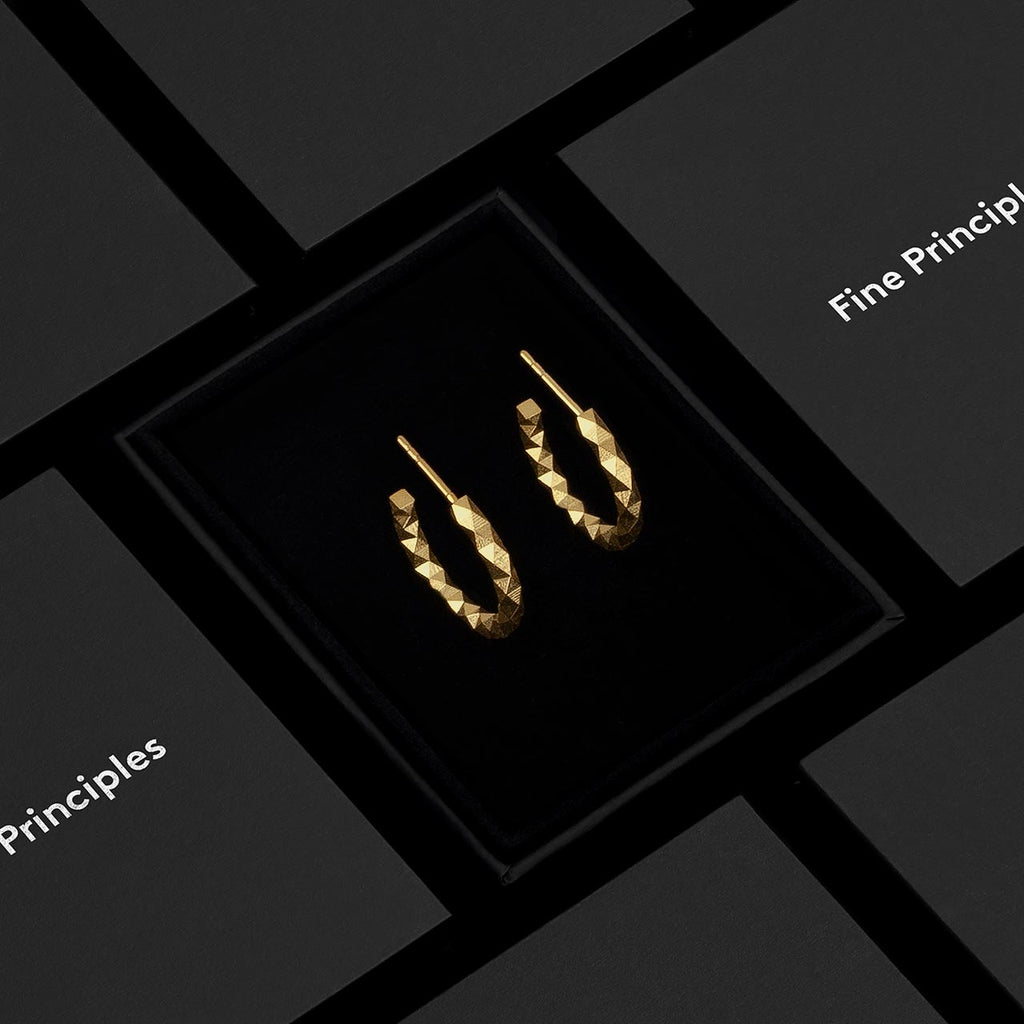 Mittelgroße Kreolen XFCO2562M von Fine Principles aus Berlin — nachhaltiger Schmuck aus recyceltem 935 Silber oder 750 Gold mit 256 unpolierten Facetten, präsentiert im schwarzen Etui mit minimalistisch-geometrischem Design.