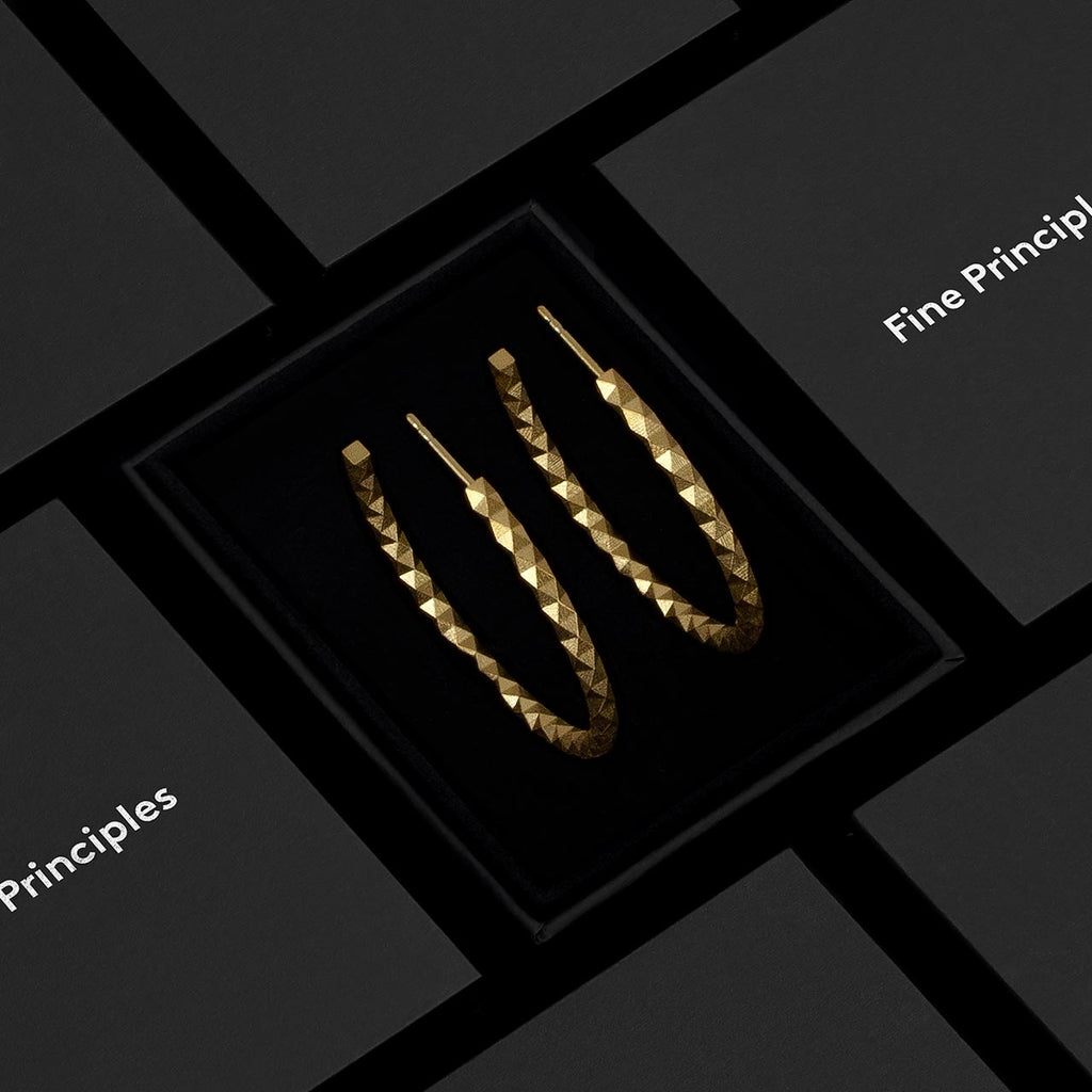 Große Kreolen XFCE2562L mit 512 unpolierten Facetten aus recyceltem 935 Silber oder 750 Gold — minimalistischer, geometrischer und nachhaltiger Schmuck von Fine Principles aus Berlin, stilvoll präsentiert im schwarzen Etui.