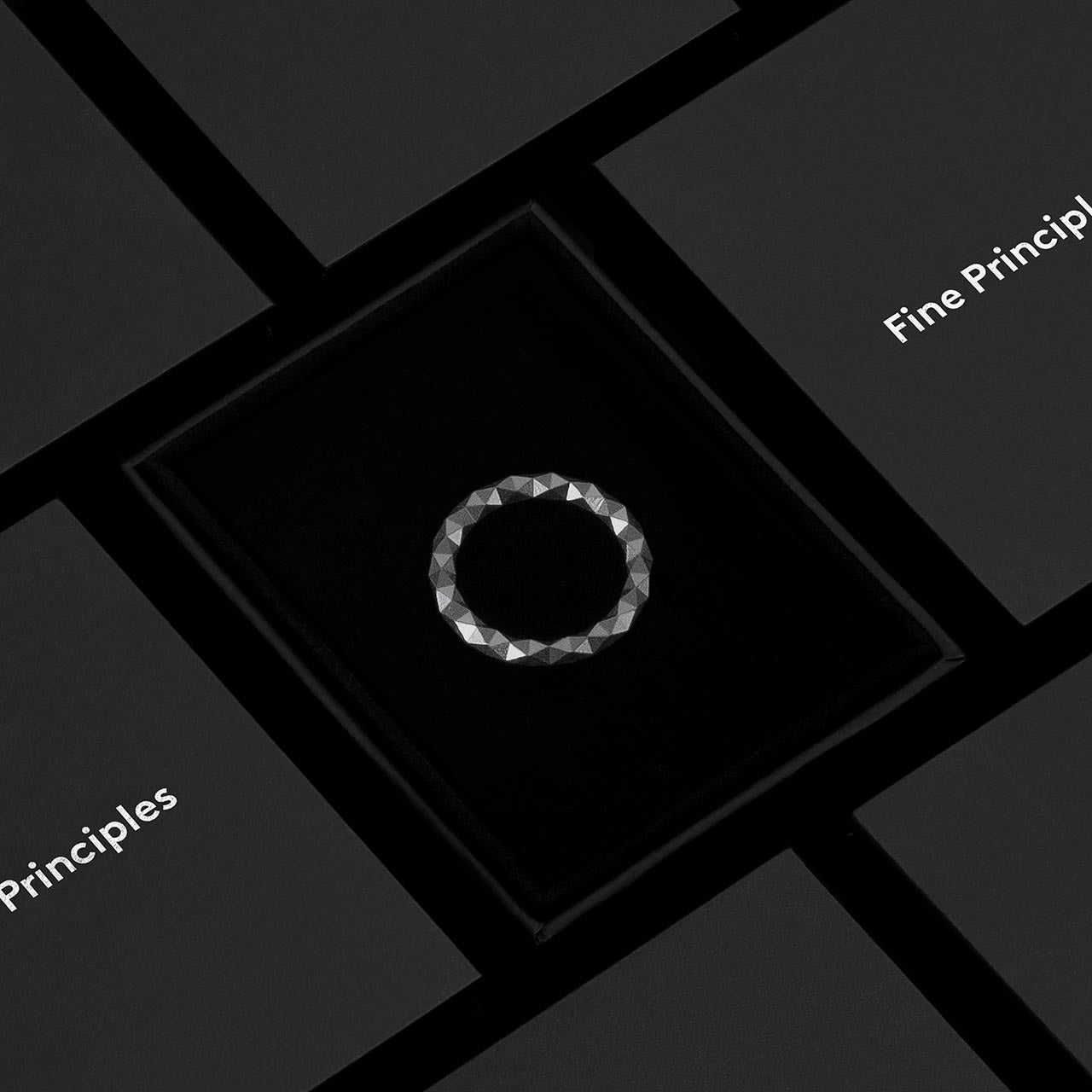 Ring XFRI2562 mit 128 Facetten und mit grafischem Anspruch, handgefertigt aus recyceltem Edelmetall — nachhaltiger Schmuck von Fine Principles Berlin, elegant inszeniert in schwarzer Box.