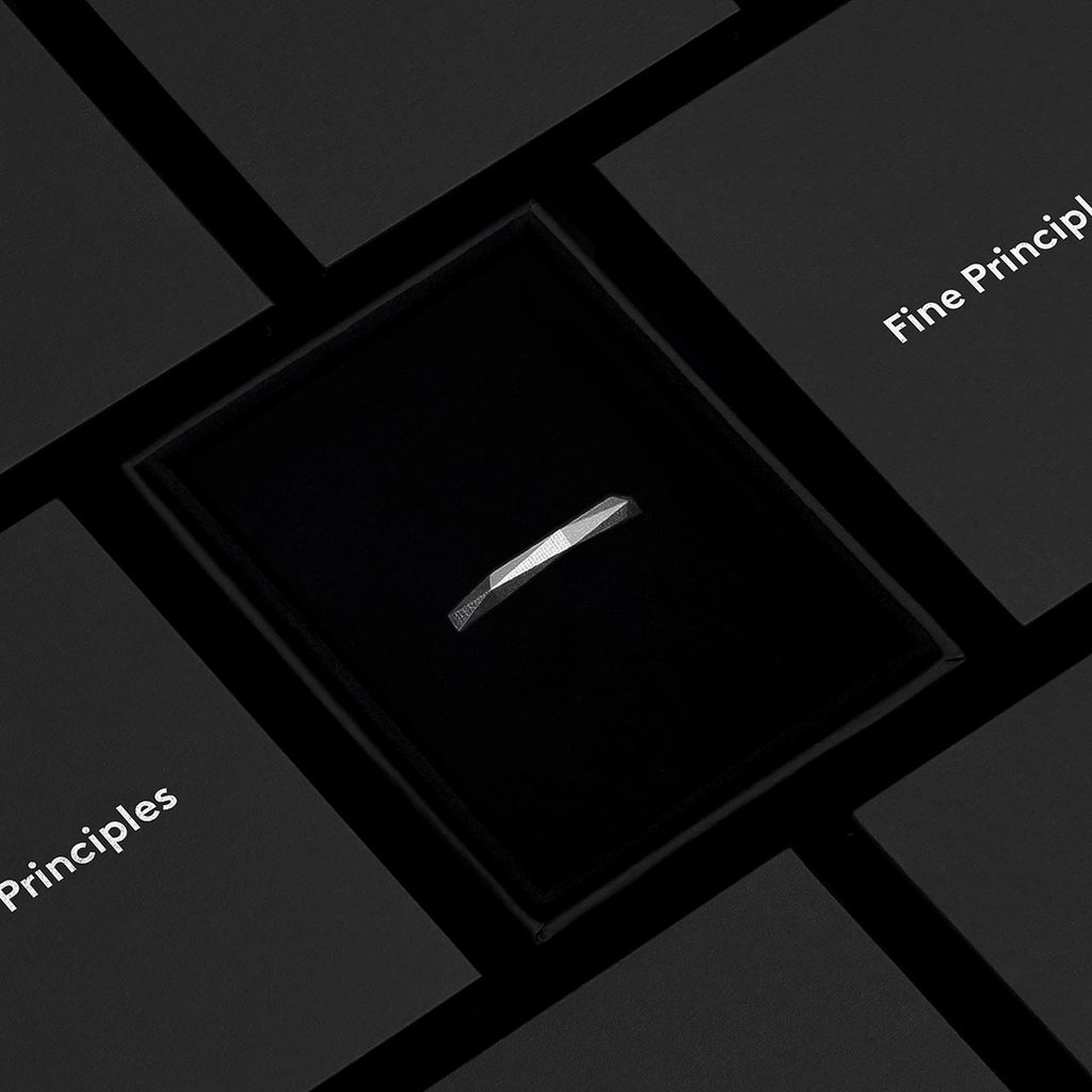 Moderner Ring XFRI642 mit klarer Geometrie, 64 Facetten — gegossen aus recyceltem Silber oder Gold, minimalistisch inszeniert im schwarzen Etui von Fine Principles Berlin.